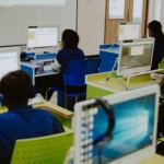 Para pelajar dan mahasiswa sedang fokus belajar pemrograman dan teknologi komputer di laboratorium komputer kampus.