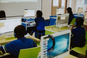 Para pelajar dan mahasiswa sedang fokus belajar pemrograman dan teknologi komputer di laboratorium komputer kampus.