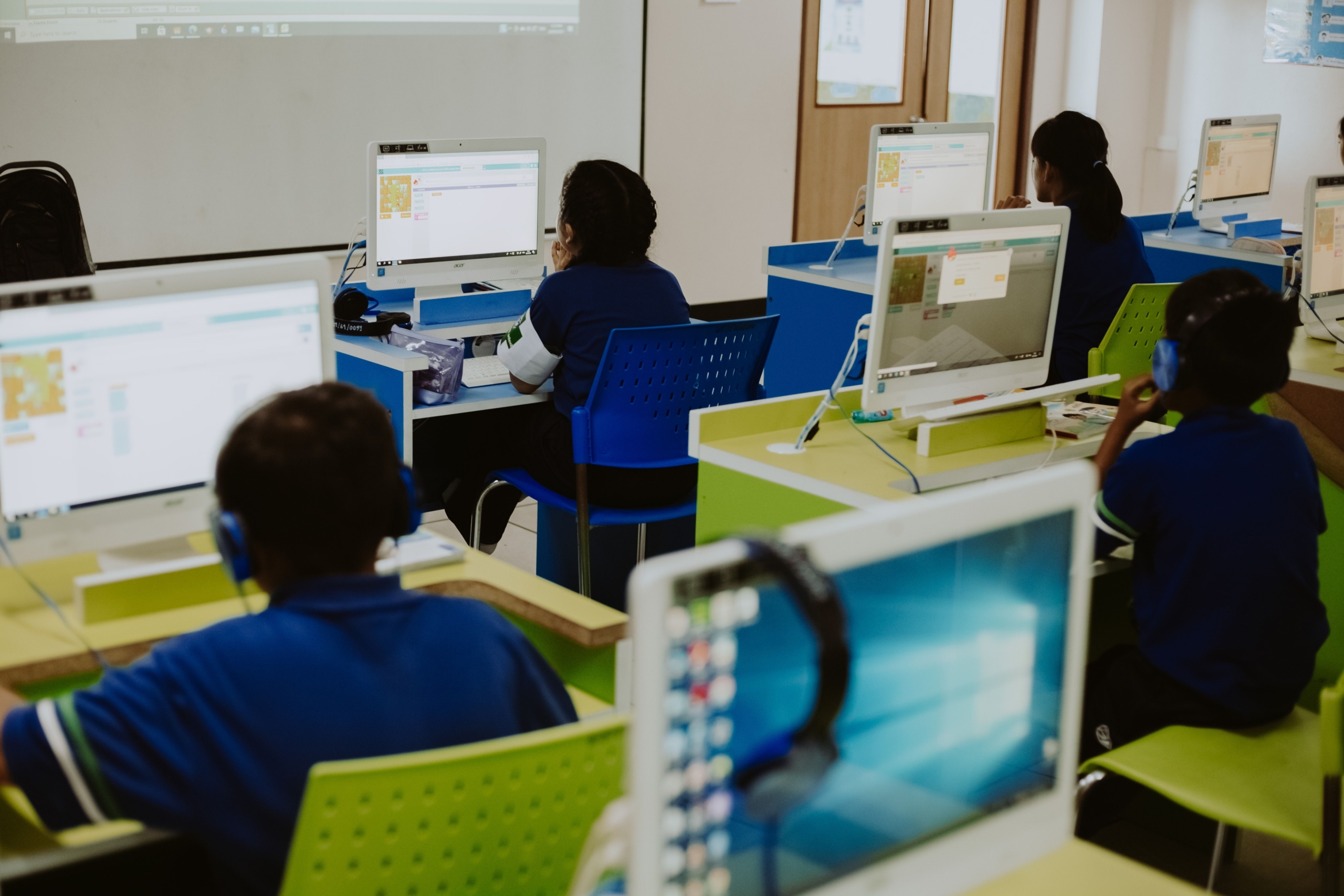 Para pelajar dan mahasiswa sedang fokus belajar pemrograman dan teknologi komputer di laboratorium komputer kampus.