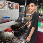 Pemilik UMKM kuliner sedang menyiapkan makanan di dapur usaha kecil sebagai ilustrasi memulai bisnis kuliner dengan modal di bawah Rp10 juta.