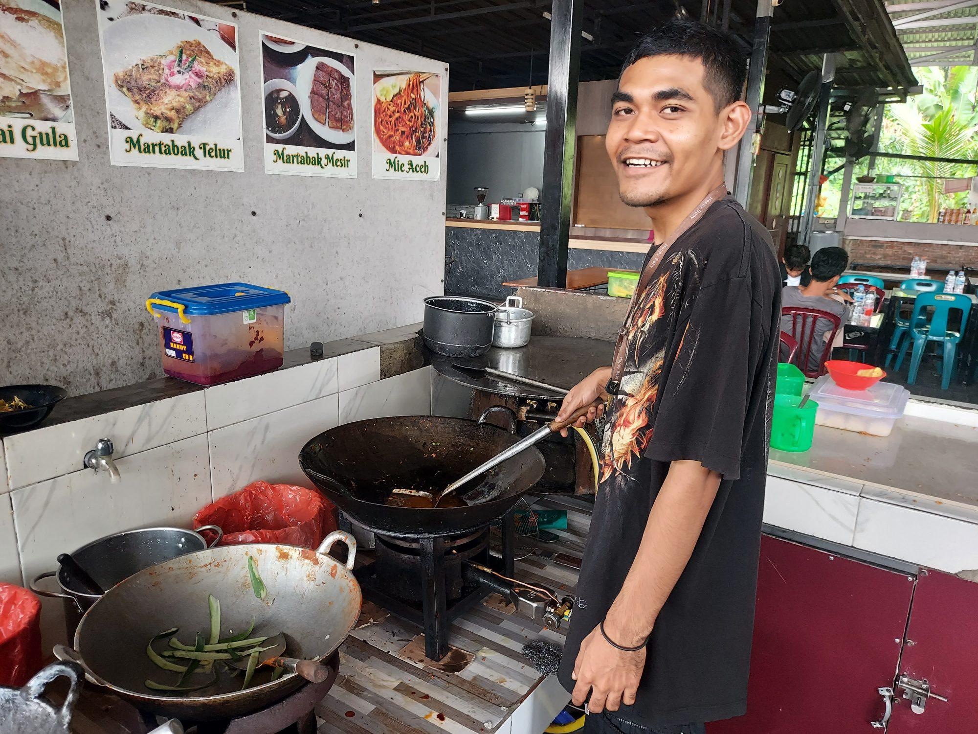 Pemilik UMKM kuliner sedang menyiapkan makanan di dapur usaha kecil sebagai ilustrasi memulai bisnis kuliner dengan modal di bawah Rp10 juta.